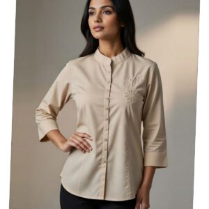 Woman wearing a beige button-down tunic with a mandarin collar and floral embroidery on the chest.